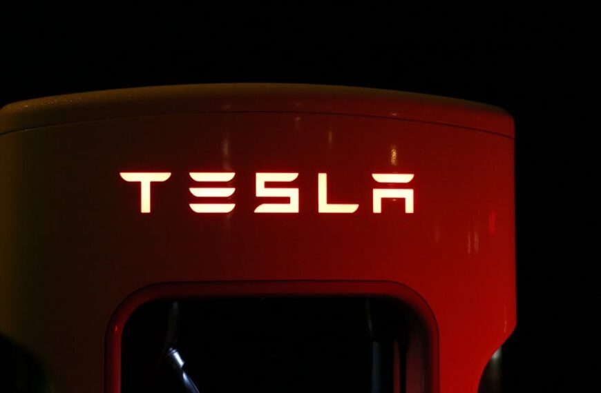Close-up of a Tesla charging station illuminated at night, showcasing modern automotive technology.