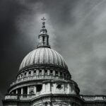 Black and white photo of the iconic St. Paul's Cathedral dome against dramatic skies.