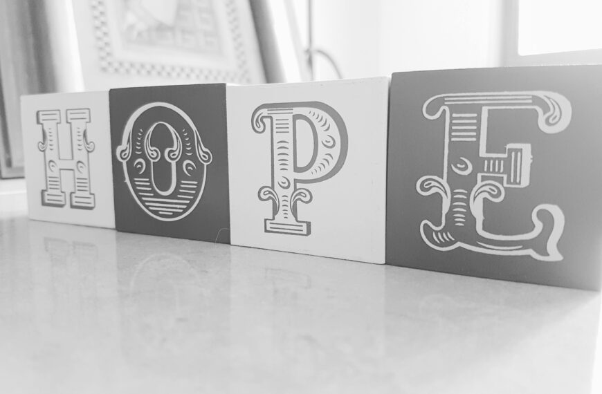 Elegant monochrome blocks spell out 'HOPE' on a reflective surface.