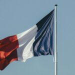 The French national flag waving against a bright blue sky, symbolizing liberty and national pride.