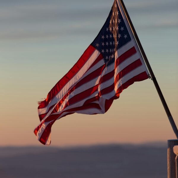 A vibrant US flag waves against a scenic sunset backdrop in Stowe, Vermont.